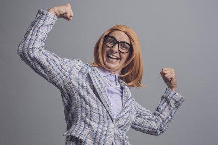 Funny cheerful businesswoman celebrating her success with raised fistsの写真素材