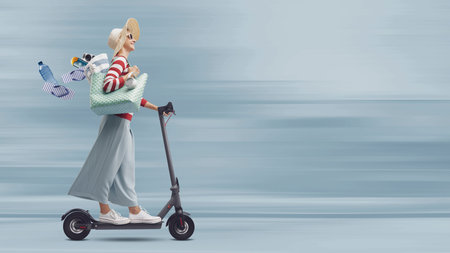 Happy fashionable woman riding a fast electric scooter and going to the beach, she is losing her...