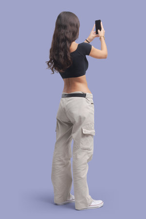 Young beautiful woman taking pictures with her smartphone, back view