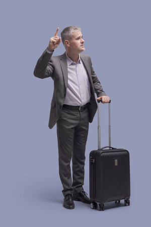 Corporate businessman on a business trip, he is calling a taxiの写真素材