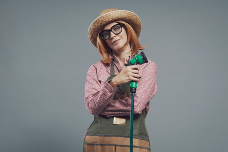 Smiling confident woman posing with garden hoseの写真素材