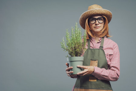 Happy woman holding a lush rosemary plant, gardening and hobby conceptの写真素材