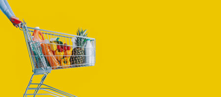 Woman pushing a supermarket shopping cart full of groceries, commerce and retail concept, copy spaceの写真素材