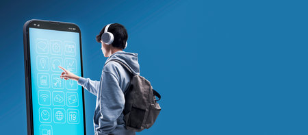 Teenager with headphones using a big smartphone, he is touching the screen and using apps, copy...