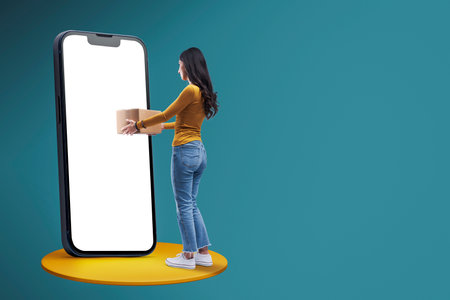 Woman receiving a box from her smartphone, online express delivery service and online shopping conceptの写真素材
