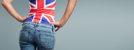 Beautiful teenager girl back view, she is wearing a British flag tank top and jeansの写真素材