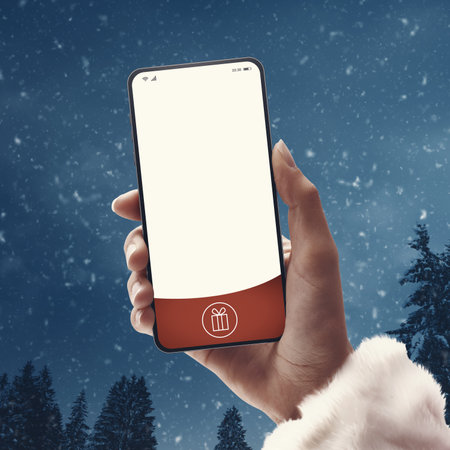 Female Santa Claus holding a smartphone with blank screen and wintry landscape in the background, Christmas and technology conceptの写真素材