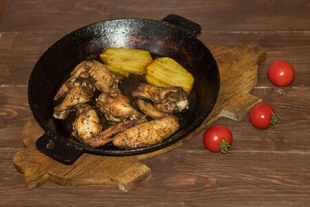 Chicken wings with potatoes fried in a panの写真素材