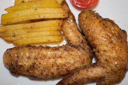 Chicken wings with potatoes laid out on a plateの写真素材