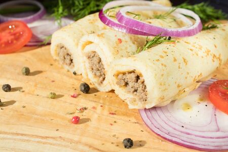 Pancakes with meat are laid out on a wooden board.の写真素材