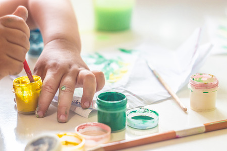 A small child draws paints on a table.の写真素材