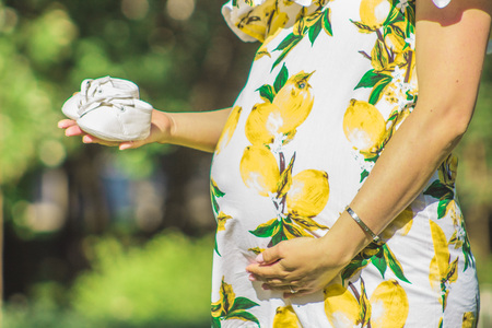 Pregnant girl holding her chopped baby shoesの写真素材