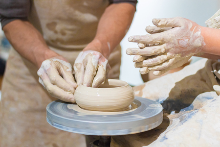 Ware from clay. The teacher helps the student to make clay dishesの写真素材