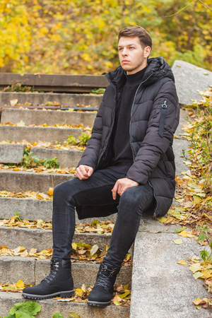 Street style. The young guy is sitting on the stepsの写真素材