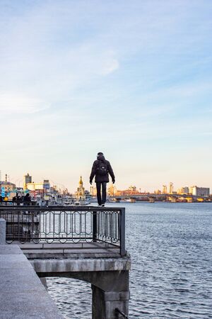 KIEV, UKRAINE - FEBRUARY 2019. The desire to feel adrenaline. The guy walks along the railing on the edge of a cliff, above the river.のeditorial素材