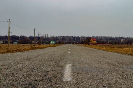 Power line along the road. Asphalt road that leads to the village.の写真素材