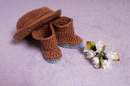 Knitted hat and boots. Knitted shoes and clothes. Booties for babies. Made by hands. Crochetの写真素材