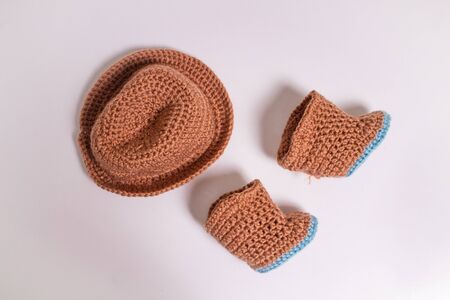 Knitted hat and boots. Knitted shoes and clothes. Booties for babies. Made by hands. Crochetの写真素材