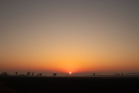 Sunrise on the horizon. Sunrise over the field. Fog above the ground.の写真素材