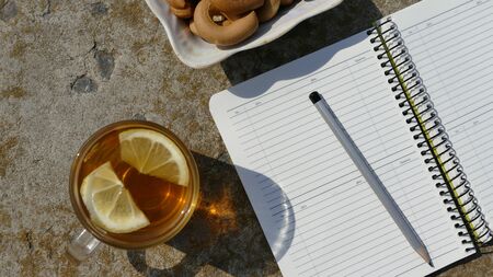 Working environment. Near the notebook is a cup of tea and a plate with bagels.の写真素材