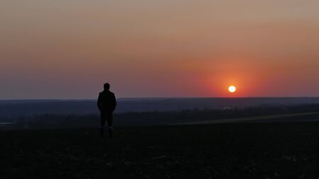A man watches the sunset. Sunset on the horizon. The sky is pink.