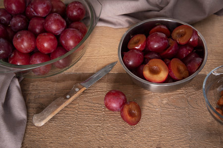 Plum in bowls on a wooden table on a sunny day. Pitted plumsの写真素材