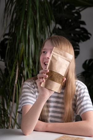 Happy girl holding microgreen mat. The concept of a healthy lifestyle, natural greens without GMOs,...