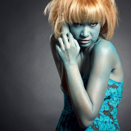 Fashion portrait of young beautiful woman looking in camera with fantasy make up in cyan colorsの写真素材