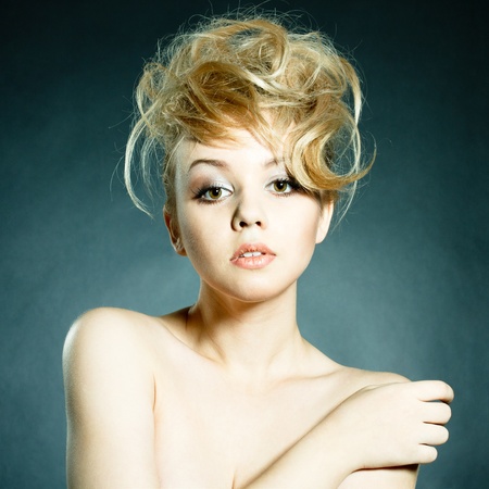 Fashion portrait of beautiful young woman posing on black background with modern styled hair