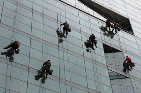 Industrial climbers on the mirrored building wash the glass.の写真素材