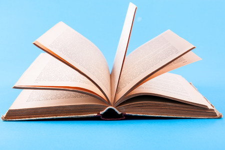 Open book laying on blue background with ome flying pages の写真素材