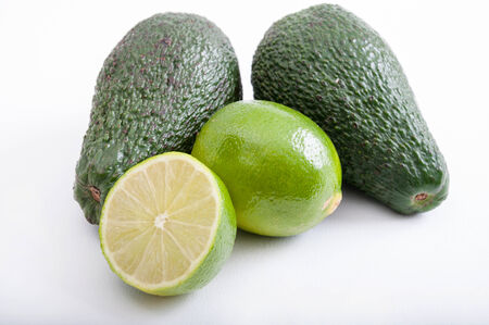 Two, whole avocados laying next to two limes の写真素材
