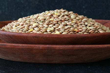 Large number of lentils packed in a wooden bowlの写真素材