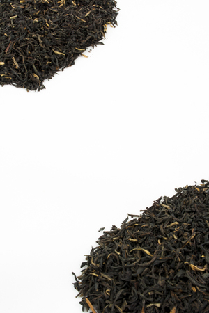 Two piles of loose leaf black tea against a white background with room for text in the middle.の写真素材