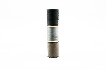 Three neutral colored thread bobbins stacked on top of each other
