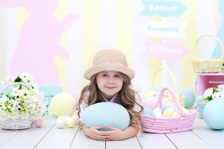Easter! Cute girl playing with easter egg. A child holds a large colorful egg on the background of...