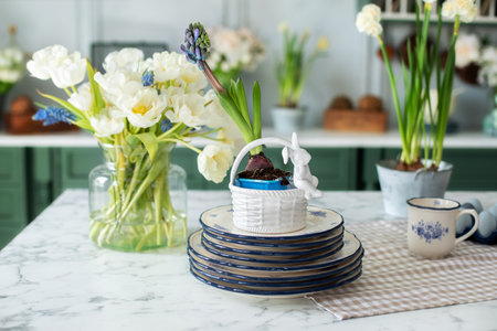 Bouquet of flowers in vase and porcelain plates on table. Greeting card. Home interior with easter...