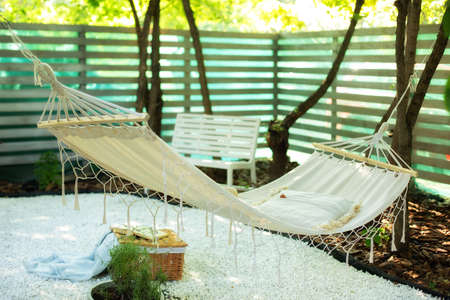 Comfortable Hammock hanging hanging on tree in autumn garden. Cozy hygge place for weekend relax in yard. Cozy exterior backyard. Concept of recreation outdoor. Hammock in boho style hanging on tree.の写真素材