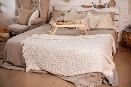 Luxury bedroom interior with beige pillows, wooden bedside table and armchairの写真素材