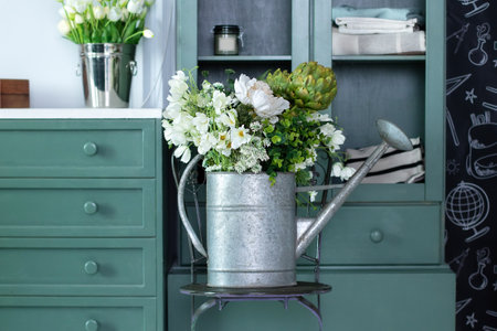 Vintage rustic garden tool at home. Summer bouquet of flowers in watering can on chair. Bunch of daisies in watering can. gardening concept.の写真素材