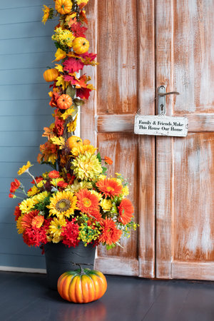 House entrance staircase decorated for autumn holidays, fall flowers and pumpkin. Cozy wooden porch...