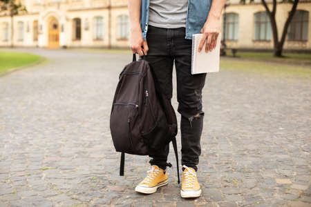 Cropped image of a young man with backpack and notebook in the cityの写真素材