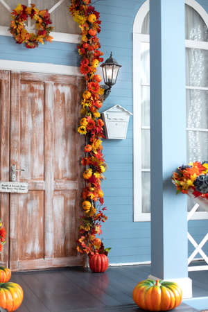 A vertical shot of an entrance to a house decorated with autumn leaves