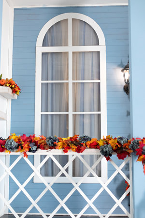 wooden staircase railings decorated Fall festive yellow leaves, twigs and pumpkins. Entrance of house door decorated autumn for holiday. Halloween decoration of handrails stairs poの写真素材