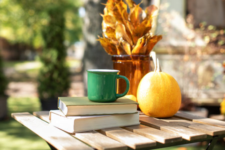 Autumn weekend concept. Ðygge lifestyle concept. Cozy warm autumn composition with cup of hot tea, stack books and pumpkin on table. Autumn home decor. Fall mood.の写真素材