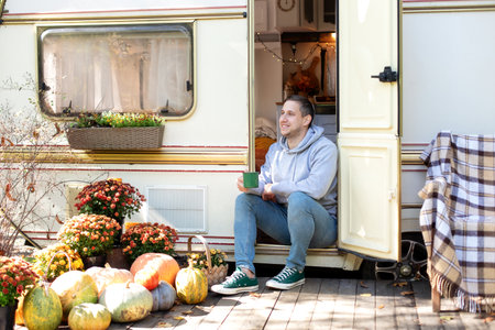 Man sitting in front of camper van on a sunny autumn dayの写真素材