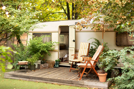 RV camper van with chairs and table in the garden.
