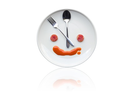 Metal spoon and fork arrange as clock face on white dish with artistic human like face from foodの写真素材