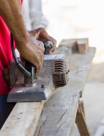 Carpenter working with electric planer  in his workshop, close up on the tool with handsの写真素材