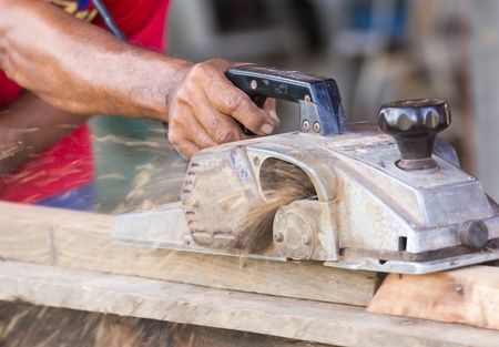 Carpenter working with electric planer  in his workshop, close up on the tool with hands
